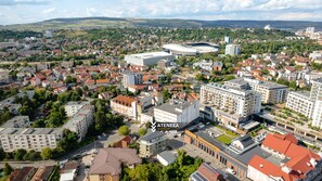An aerial view of a cityscape with a prominent stadium and various buildings, including a large apartment complex labeled "ATENEA".