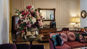 A well-appointed living room with a large floral arrangement, a vintage radio, a coffee machine, and a plush sofa with decorative pillows. - Ateneea Luxury Rooms (Cluj-Napoca)