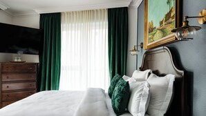 A neatly arranged bedroom with a bed, a dresser, a television, and a painting on the wall. - Ateneea Luxury Rooms (Cluj-Napoca)