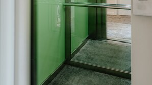 A modern elevator with green walls and a digital display showing the number 3. - Ateneea Luxury Rooms (Cluj-Napoca)