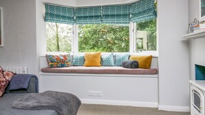 Een kamer met erker, een bed, een kapstok en een radiator.