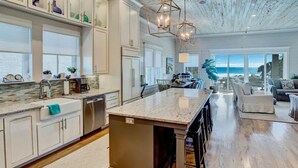 A spacious kitchen with a large island, wooden flooring, and a view of the beach. - Eastern Lake Beach Access, Heated Pool, 6 Seater Golf Cart!! (Santa Rosa Beach)