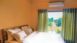 A neatly made bed with white linens in a room with a window. - Jawai Sanderao Farms (Sumerpur)