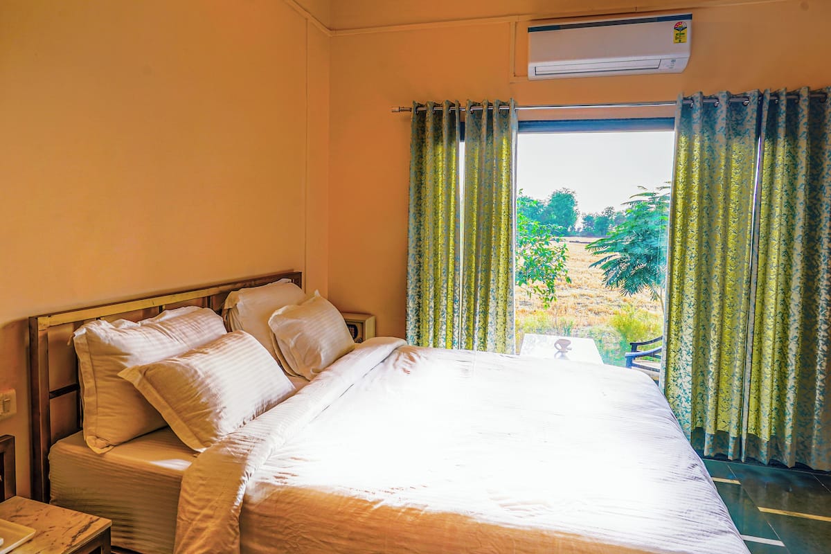 A neatly made bed with white linens in a room with a window.