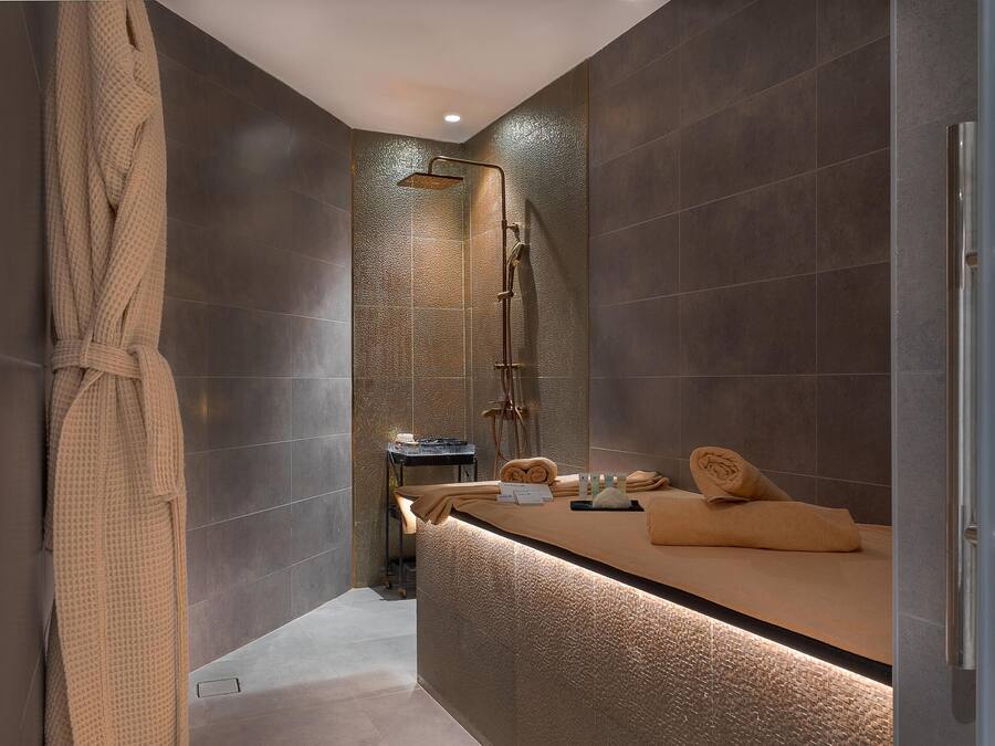 A modern bathroom with a glass shower enclosure, a towel rack, and a counter with towels.