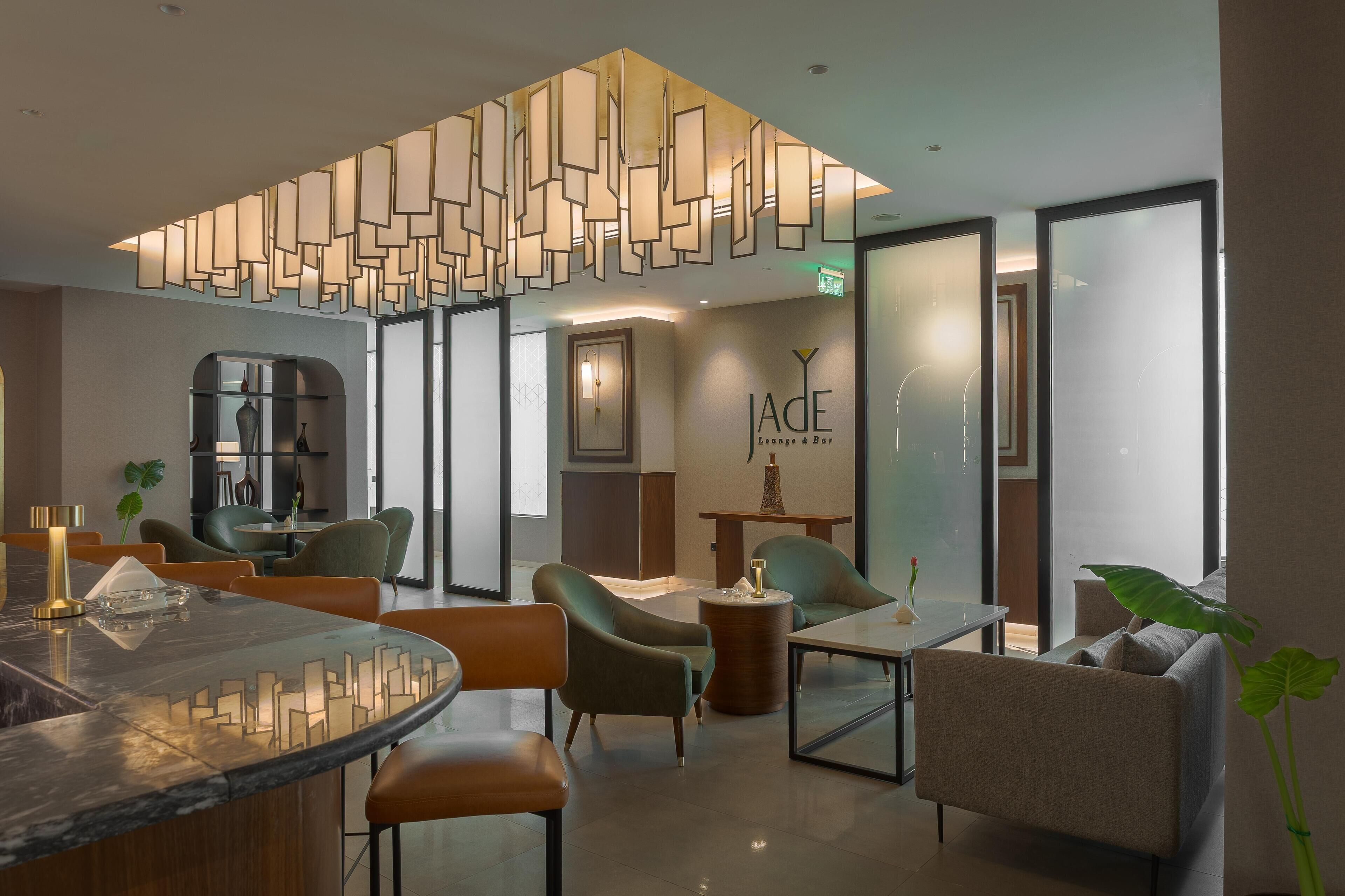 A modern lounge area with a marble bar, comfortable seating, and a decorative ceiling light fixture.