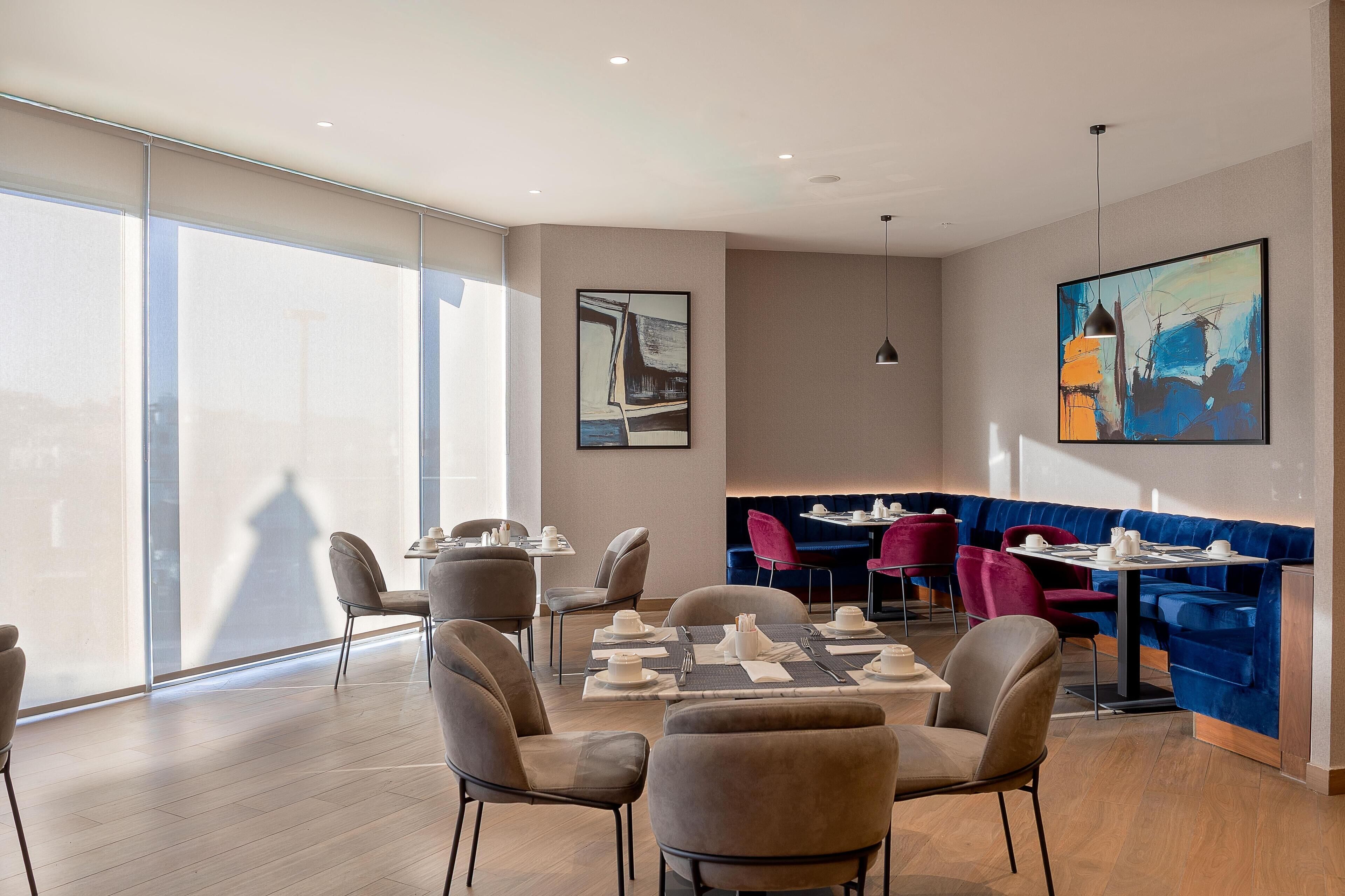 A modern dining area with a mix of seating options, including round tables and a blue booth seating area.