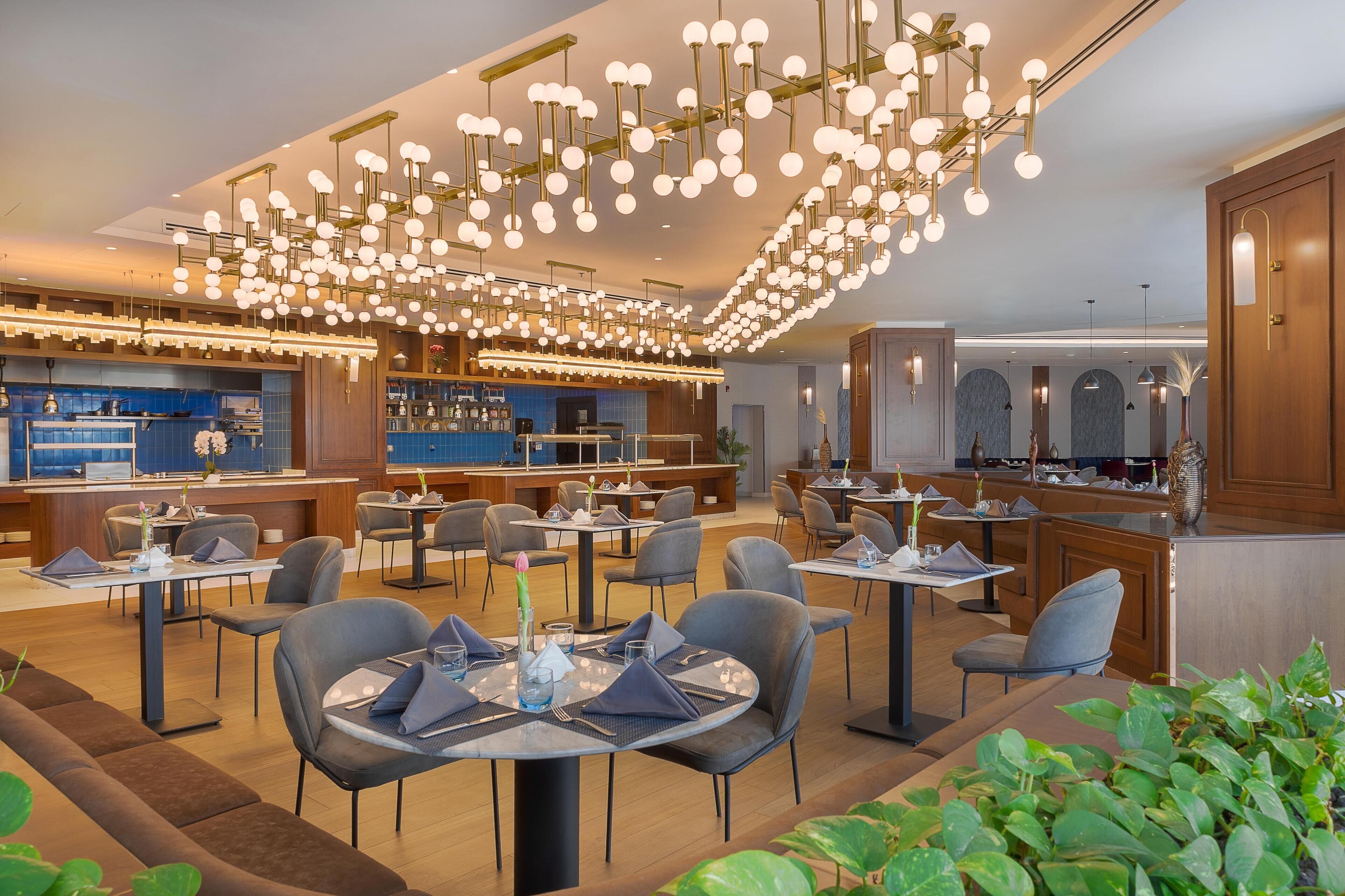 Un restaurante moderno con varias zonas de comedor, un bar y una recepción.