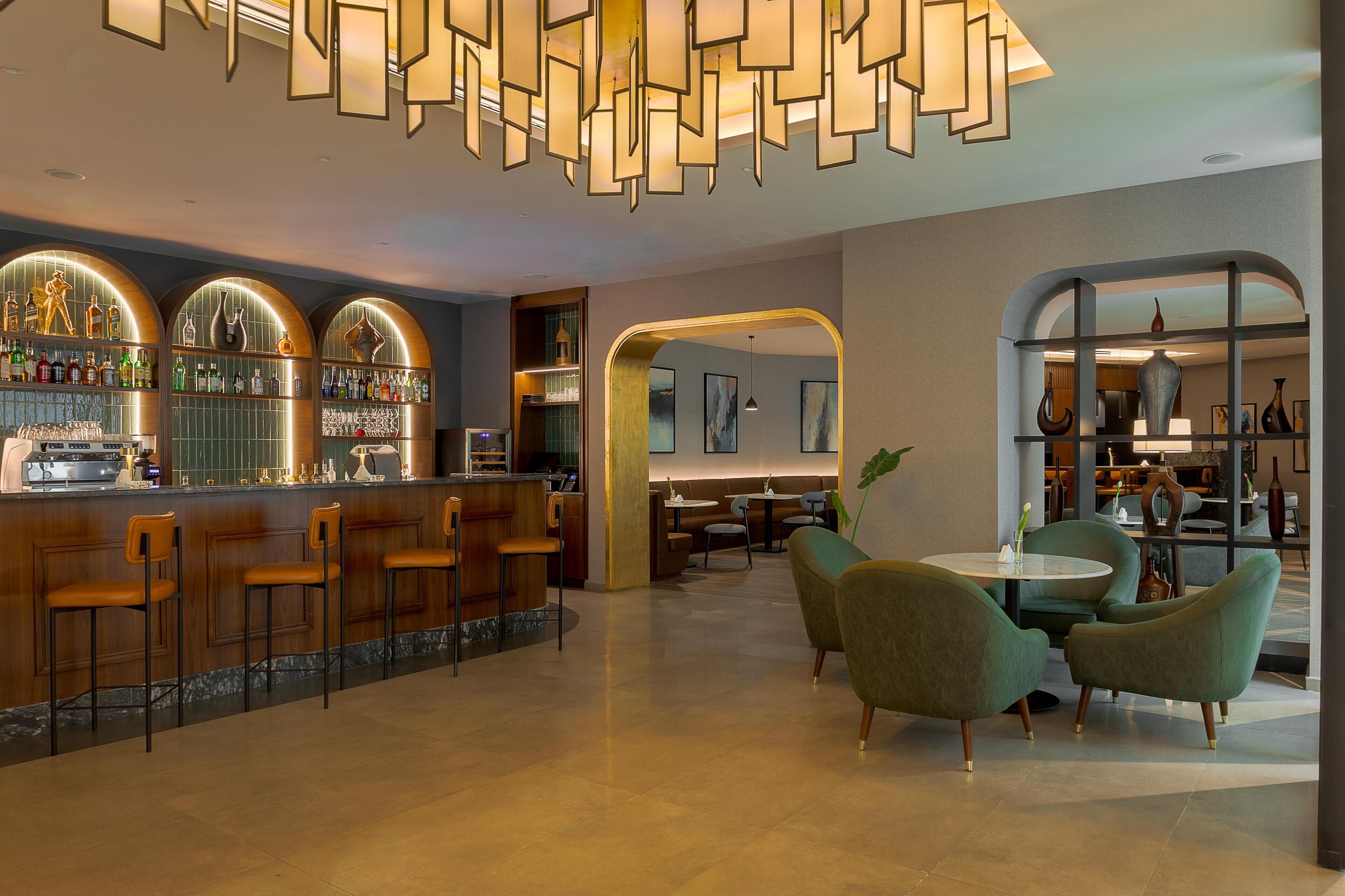 A bar area with a counter, bar stools, and a seating area with round tables and chairs.