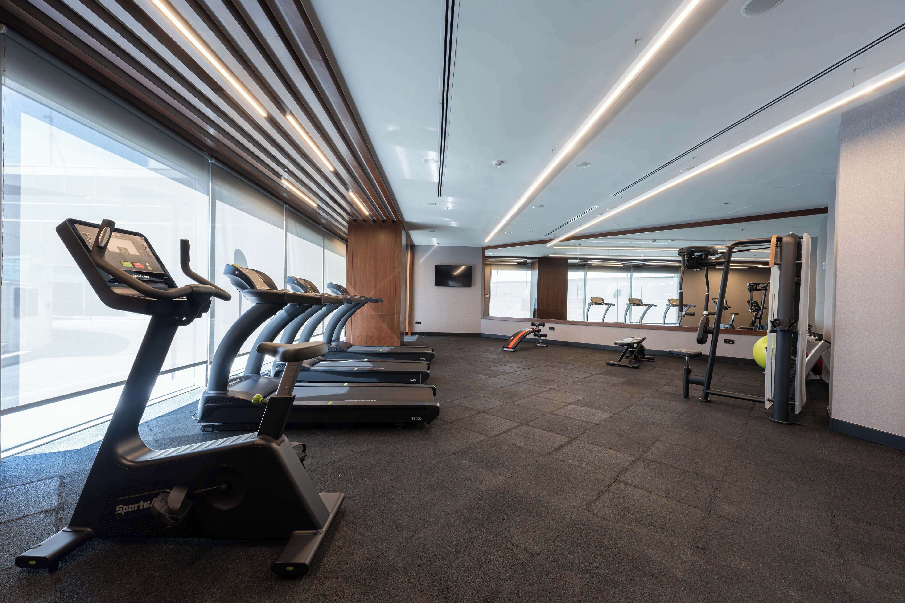 Un gimnasio moderno con cintas de correr, una máquina de pesas y una colchoneta de yoga.