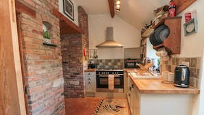 Eine Küche mit Backsteinwand, Herd, Backofen und gefliestem Spritzschutz.