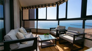 Un balcón con sofá, sillones y una mesa de centro, con vista al mar.
