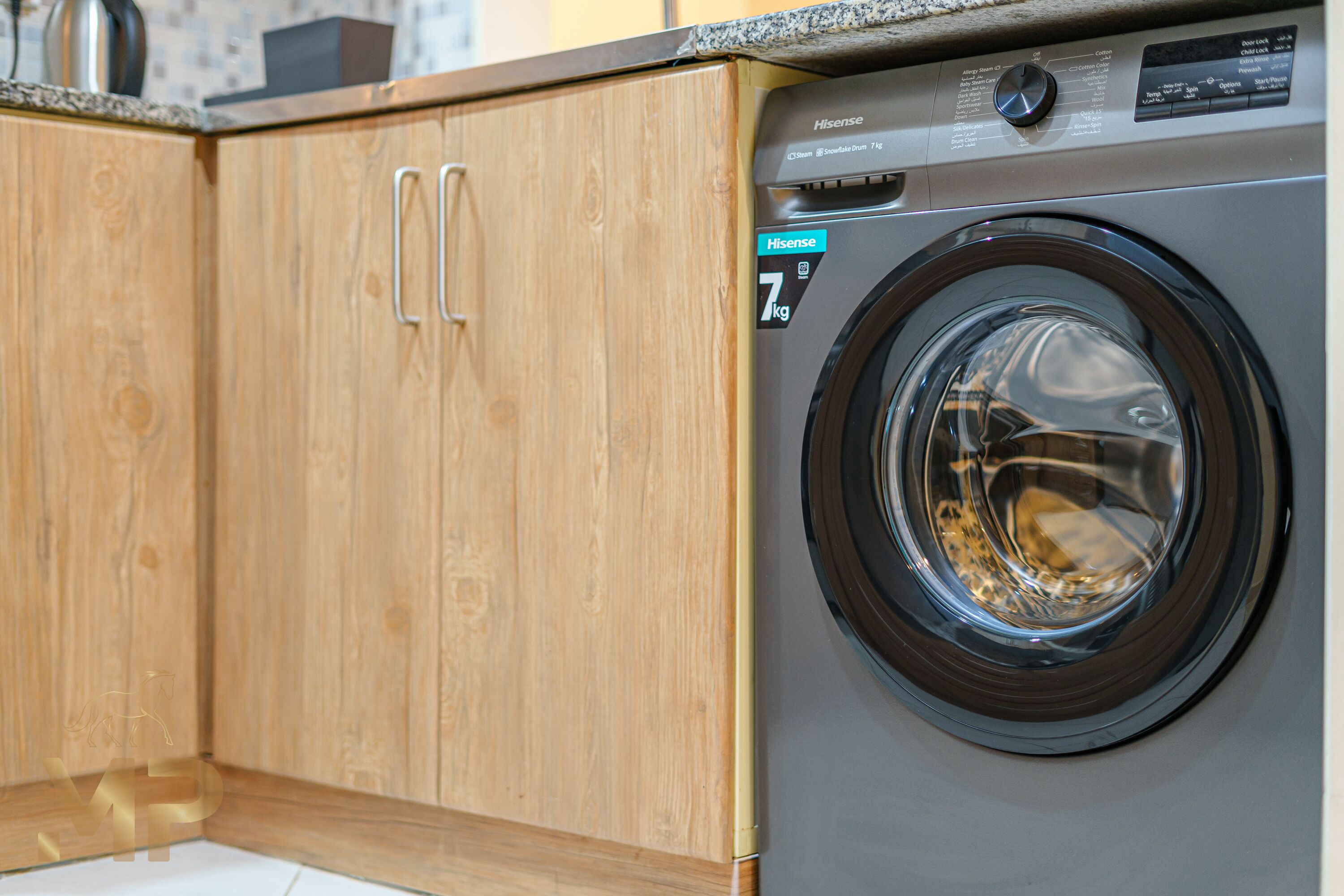 A front-loading washing machine with a control panel and a wooden cabinet with metal handles.