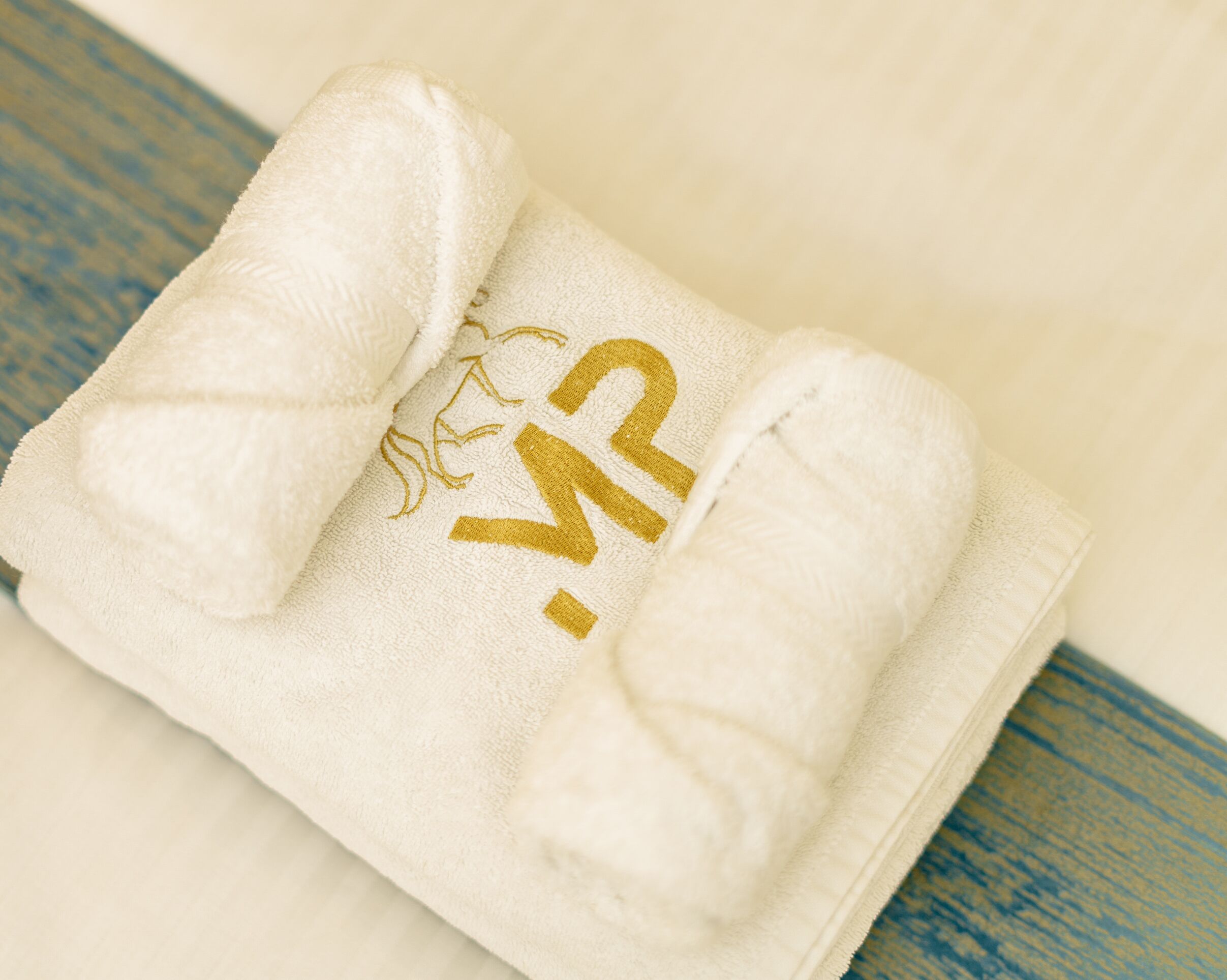 A white towel with embroidered text on a wooden surface.