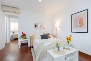 Una habitación de hotel con cama, mesita de noche, lámpara y una obra de arte.