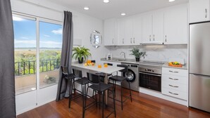 A modern kitchen with a large window, a washing machine, and a refrigerator. - Coral SeaShell by Fidalsa (Lomas de Polo-Pinomar)