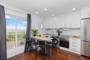 A modern kitchen with a large window, a washing machine, and a refrigerator.