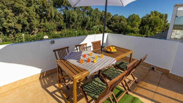 A terrace with a table, chairs, and an umbrella.
