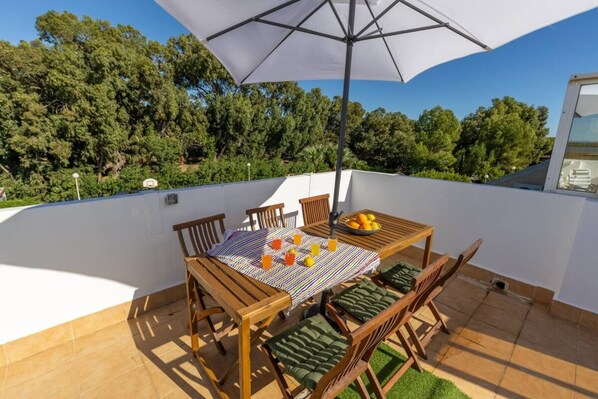 Una terraza con una mesa, sillas y una sombrilla.