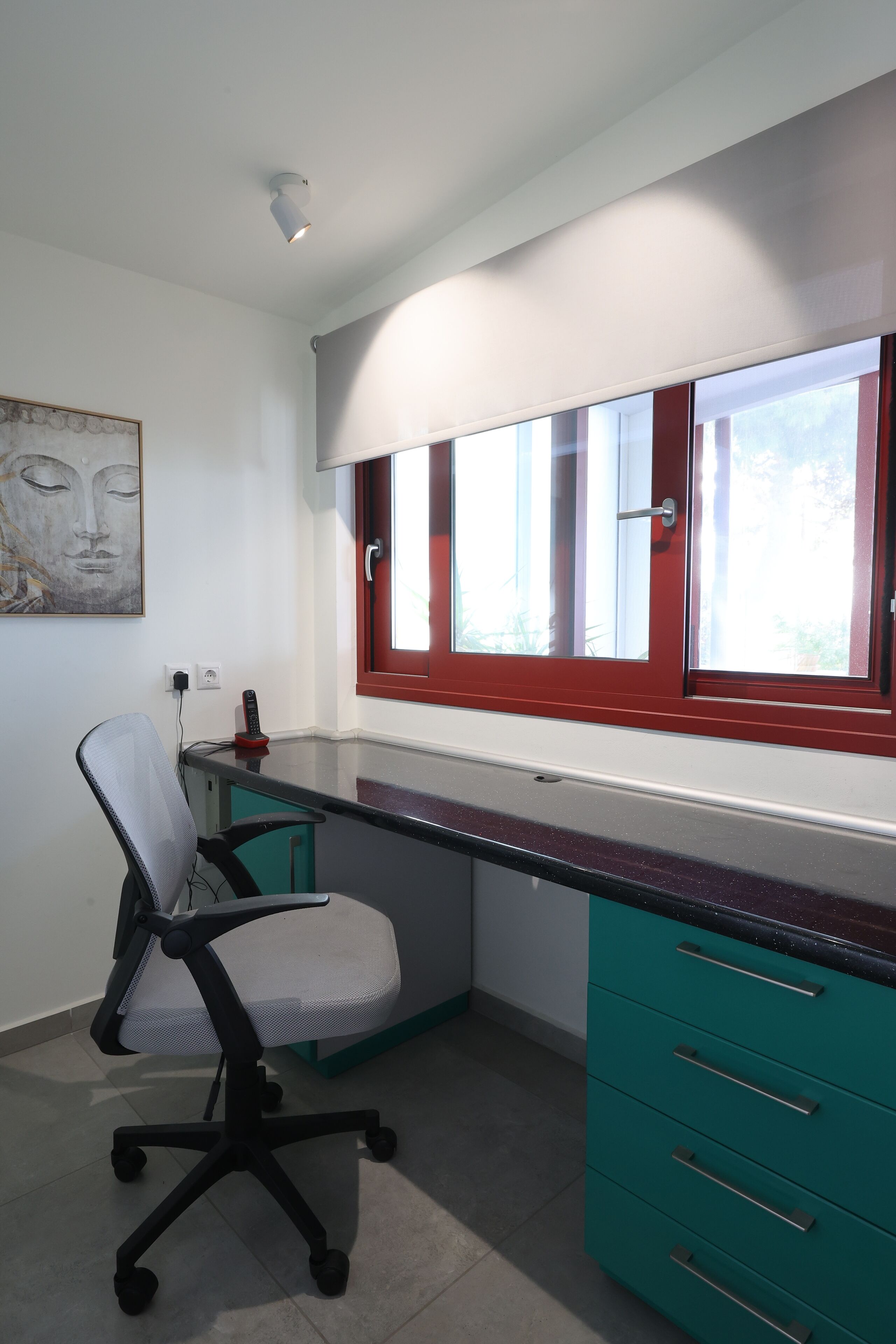 Un espace de bureau moderne comprenant un bureau, une chaise et des tiroirs de couleur turquoise.