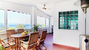 A dining area with a table, chairs, and a view of the sea.