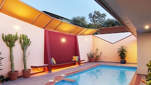 A swimming pool with a red bench and potted plants.