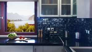 A kitchen with a view of mountains and a lake, featuring a black countertop, white cabinets, and a window with a view.