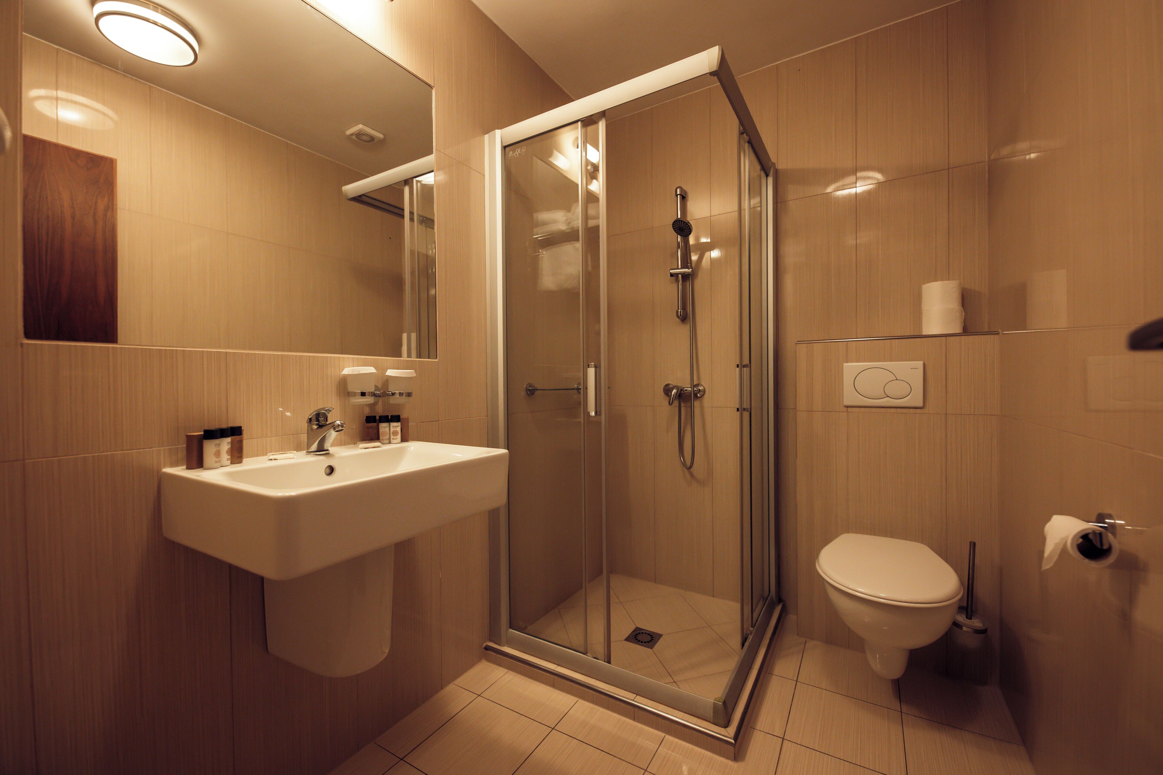 Een moderne badkamer met een douchecabine van glas, een wastafel en een toilet.