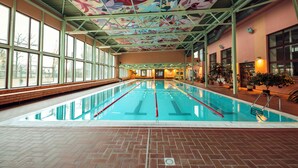 An indoor swimming pool with clear lanes, a tiled floor, and a colorful ceiling.