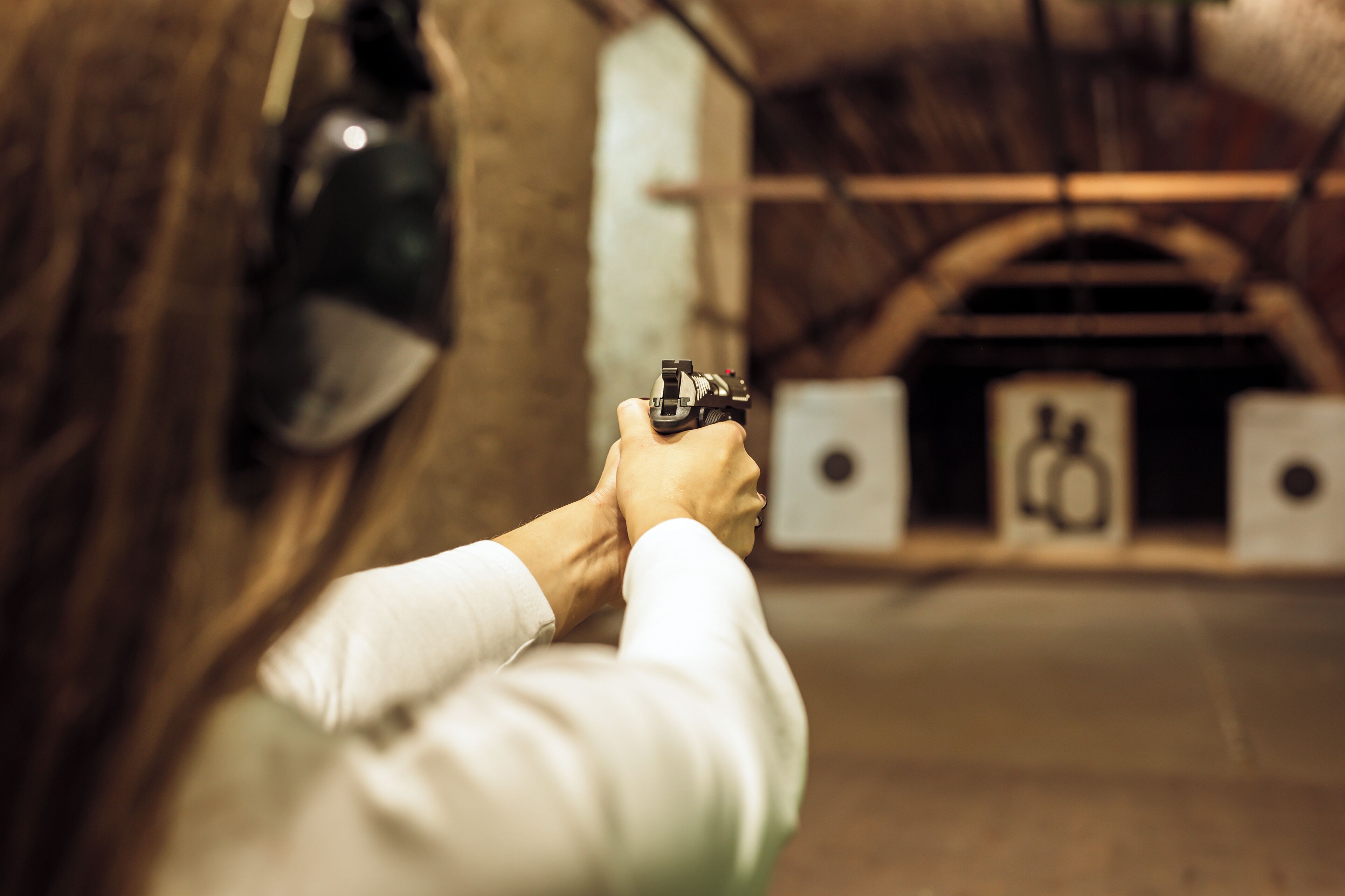 A person aiming a handgun at a target in a shooting range.