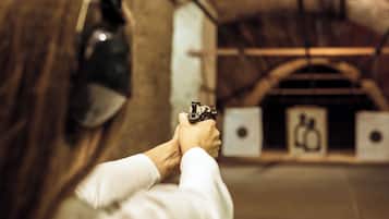 A person aiming a handgun at a target in a shooting range.