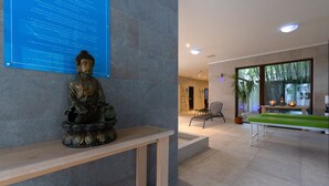 A Buddha statue on a pedestal, a blue informational sign, a billiards table, and a seating area with chairs and a potted plant.