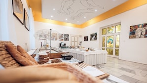 A modern dining area with a long table set for a meal, a coffee machine, and artwork on the walls.