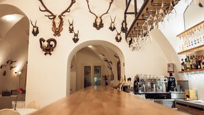 A restaurant with a long wooden counter, mounted deer skulls on the wall, and a bar area with shelves of bottles.