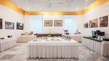 A conference room with a long table set for a meeting, surrounded by chairs, and decorated with artwork on the walls.