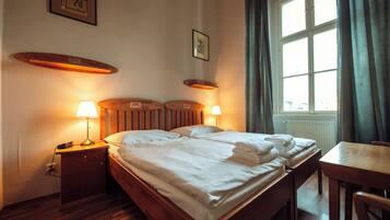 Une chambre d’hôtel avec un lit en bois, des lampes de chevet, une table de chevet en bois, un bureau en bois et une fenêtre avec des rideaux.