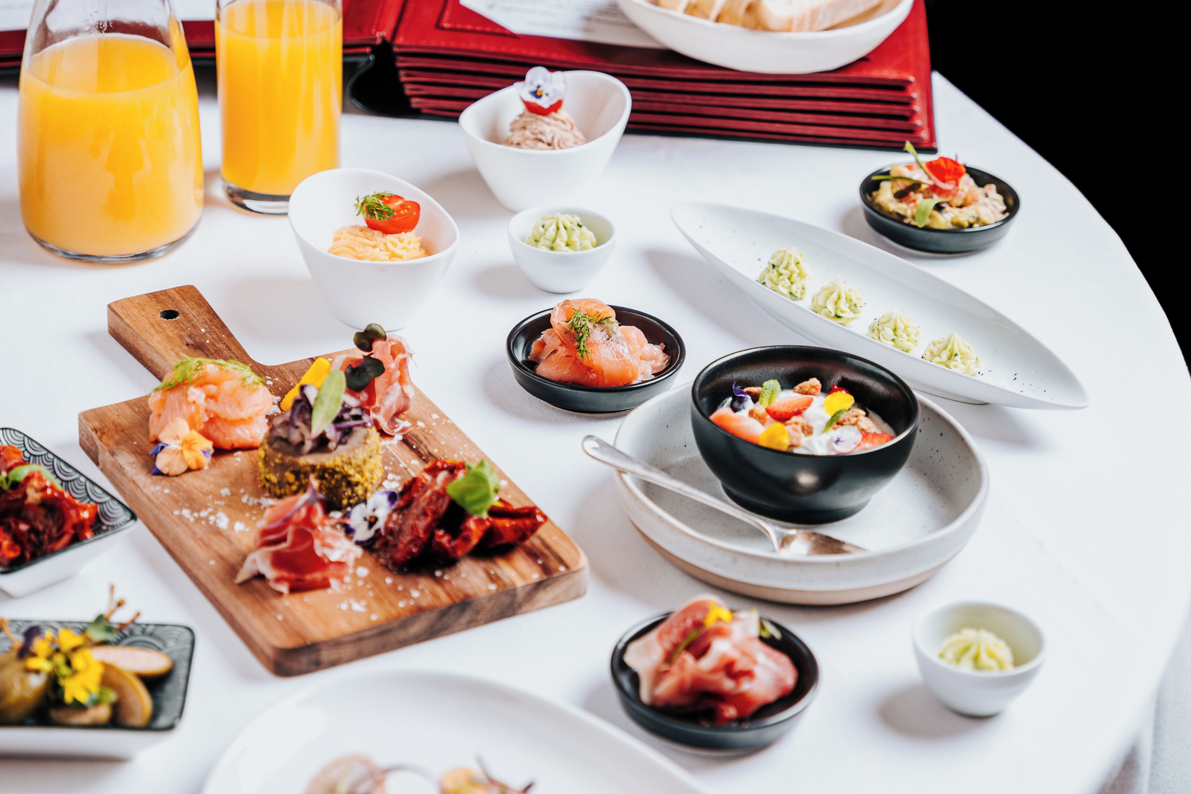 A breakfast setting with various dishes, including smoked salmon, eggs, and a bowl of soup.