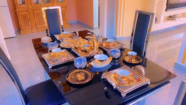 Una mesa de comedor dispuesta con vajilla decorada y un televisor montado en la pared.