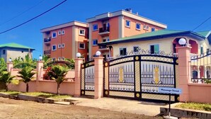 Un edificio residencial de varios pisos con entrada porticada, un letrero que dice 'Massango Street' y un cielo despejado.