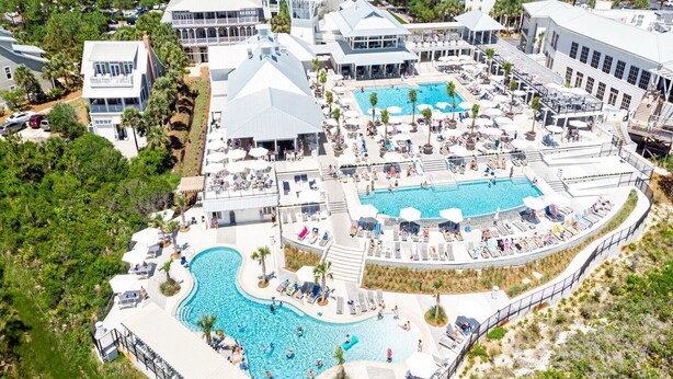A resort with multiple swimming pools, sun loungers, and a large outdoor dining area.