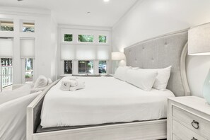 A modern hotel room with a large bed, a bedside table, a lamp, and a view of the outdoors through multiple windows. - WaterColor Beach Club, Bikes, 3 Min Walk to Seaside (Santa Rosa Beach)