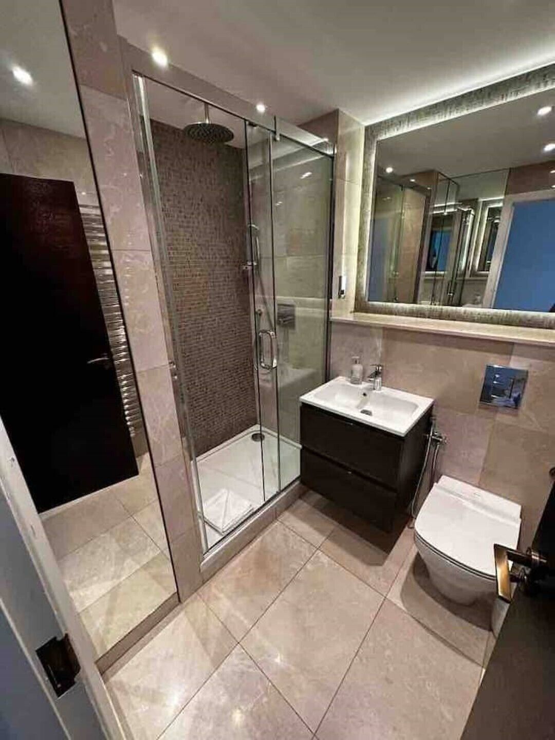 Un baño moderno con ducha de vidrio, lavamanos y retrete.