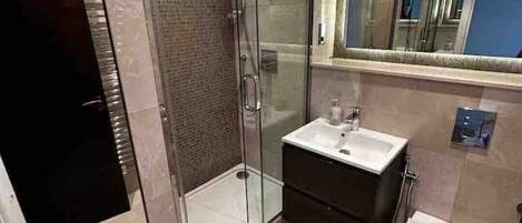 Un baño moderno con ducha de vidrio, lavamanos y retrete.