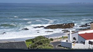 A coastal view with a beach, rocky shoreline, and a building with a red roof. - Blouberg Heights 406 (Cape Town)