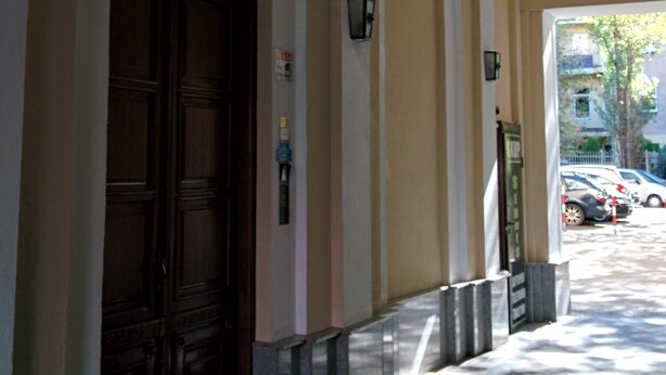 Un couloir avec une grande porte en bois, des arches au niveau des portes et des lampes suspendues de style lanterne.