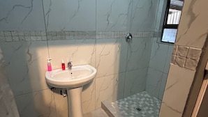 A bathroom with a white sink, a toilet, and a shower area. - 57onWYNNE (Cape Town)