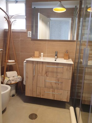 Bathroom features a sink, mirror, and drawers, along with a glass shower and toilet.