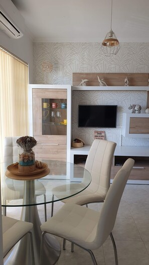 Enjoy a spacious living area with a glass dining table, flat-screen TV, and decorative wall art.