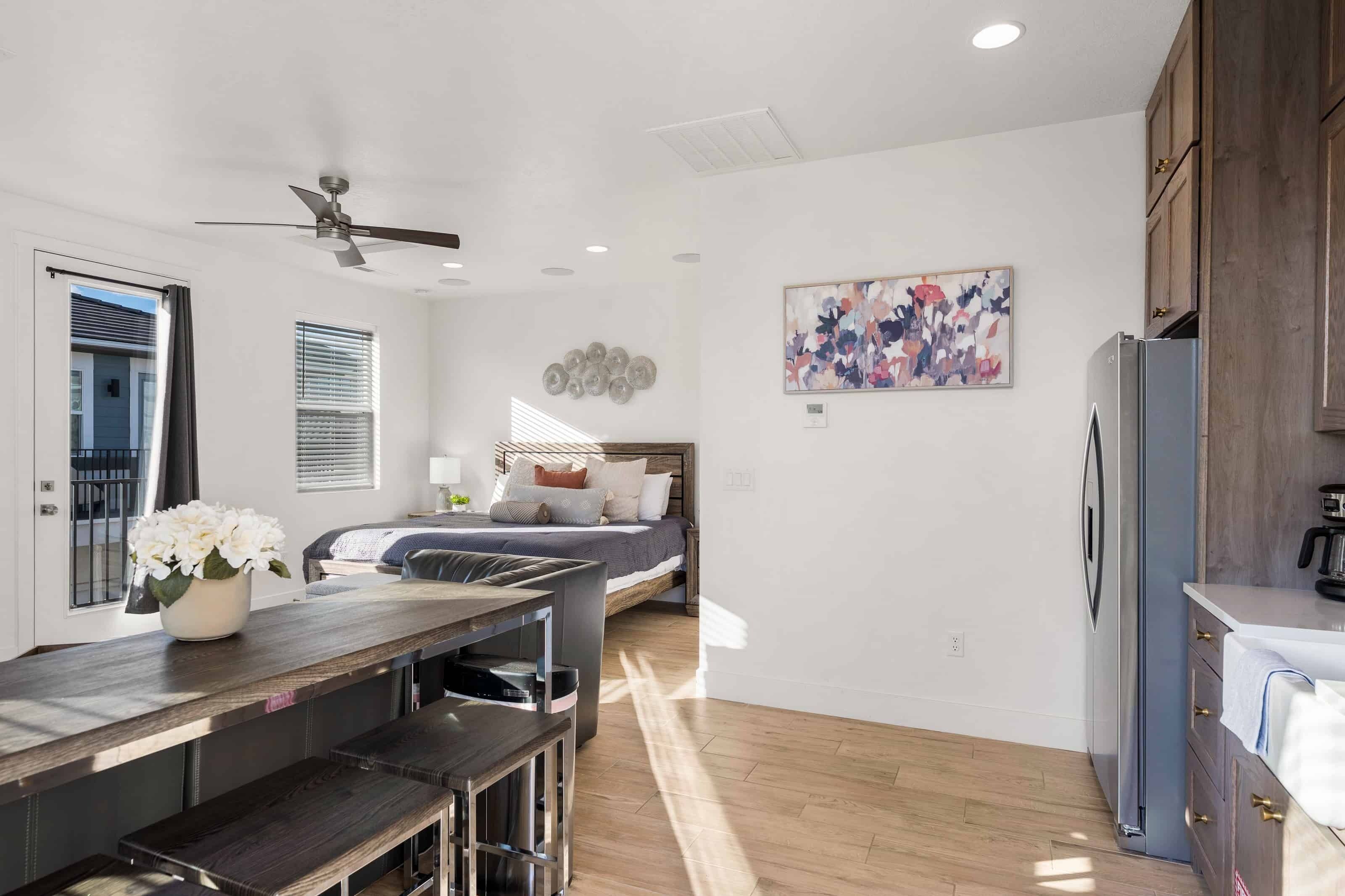 A modern kitchen with wooden cabinets, a refrigerator, and a dining area with a bench.