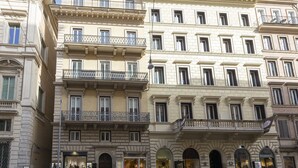 A multi-story building with balconies, arched doorways, and a storefront with a sign.